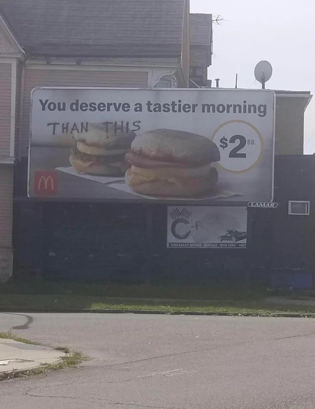 Mcdonald's billboard that says You deserve a tastier morning, and shows 2 egg McMuffins. Someone has written "than this" under the words.