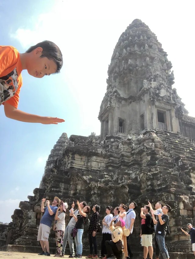 photo of Asian temple taken from an angle so it looks like a child in the sky is huge and looking down at a crowd of tiny people on the ground.