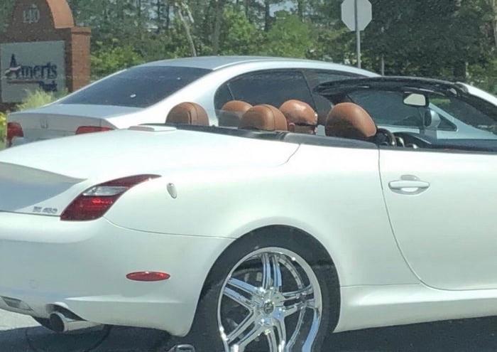 bald driver in convertible with leather seats. The headrests are the same color as the man's head, so it looks like 5 bald heads in the car.