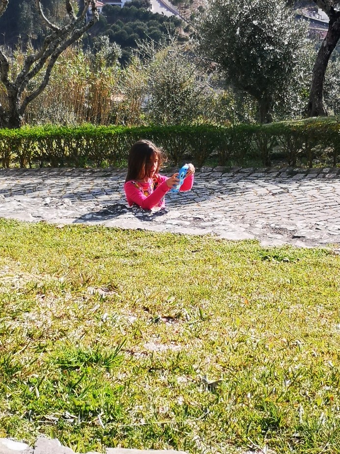 little girl playing on cobblestone patio. Camera angle makes it look like she has no lower half of her body.