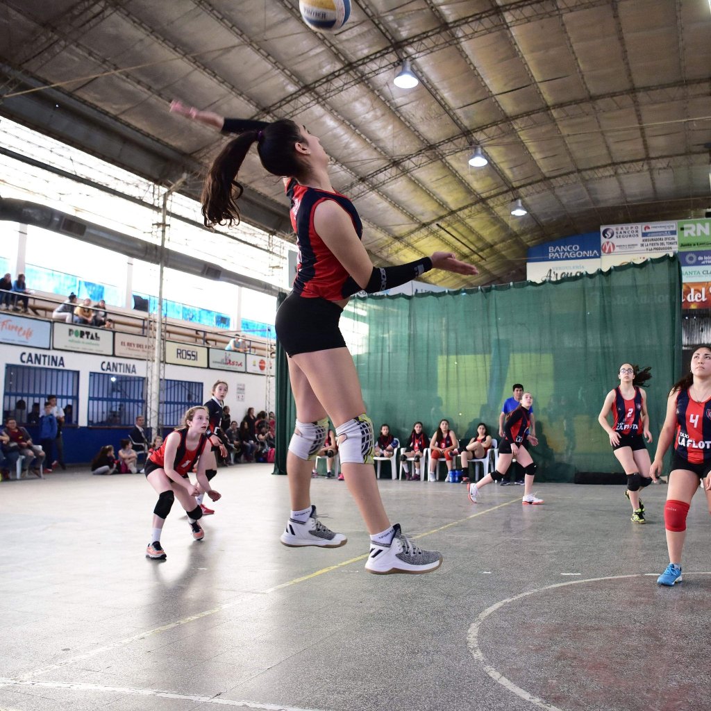 picture of girls playing volleyball. One girl in the foreground looks like a giant because of the camera angle.